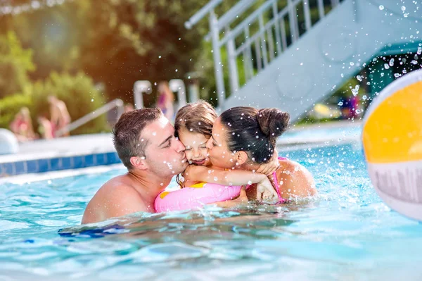 Η μητέρα, ο πατέρας φιλιά κόρη στην πισίνα. Ηλιόλουστο καλοκαιρινό. — Φωτογραφία Αρχείου