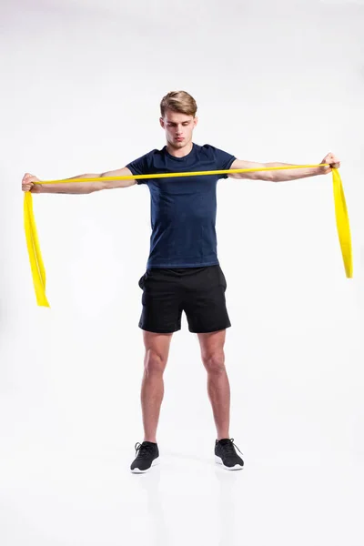 Fitnessmann trainiert mit Widerstandsbändern, Studioaufnahme. — Stockfoto