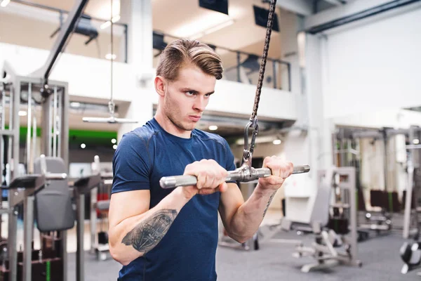 Passar ung man i gym tränar på pull-down maskin. — Stockfoto