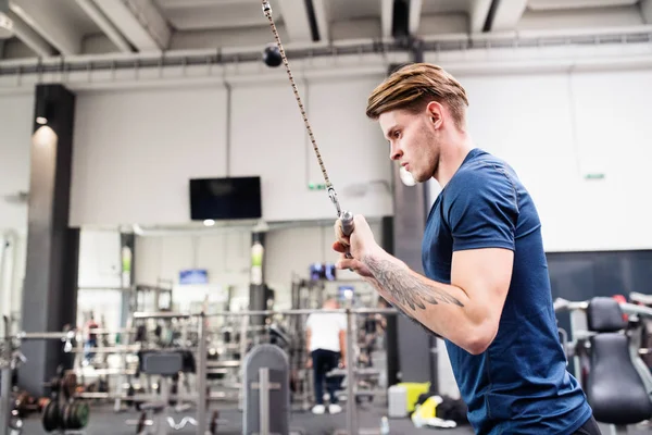 Passar ung man i gym tränar på pull-down maskin. — Stockfoto