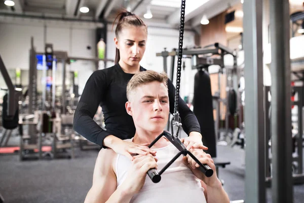 Passar ung man i gym tränar på pull-down maskin. — Stockfoto