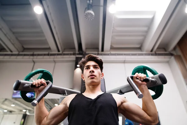 Spansktalande man utbildning i gym, gör maskinen axeln trycker du. — Stockfoto