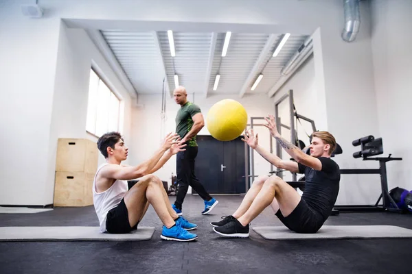 Män i gym med tränare som tränar med medicinbollar. — Stockfoto