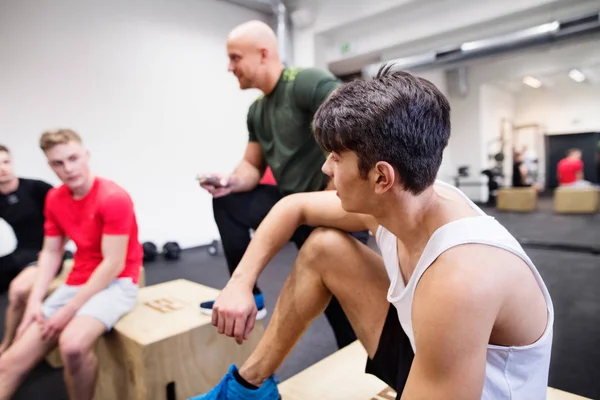 Les hommes dans la salle de gym se reposent après l'exercice sur des boîtes en forme . — Photo