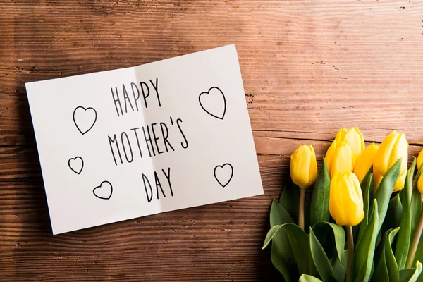 Composición del día de las madres. Tarjeta de felicitación y tulipanes. Captura de estudio . — Foto de Stock