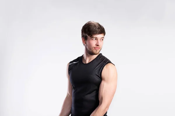 Guapo hombre de fitness en camisa negra sin mangas, tiro al estudio . —  Fotos de Stock
