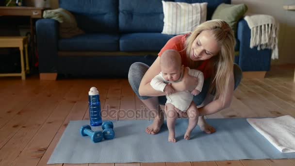 Madre hace fitness con su pequeño bebé en casa . — Vídeos de Stock