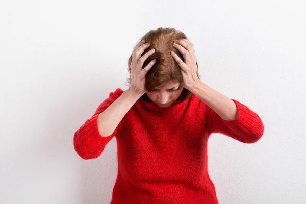 Mujer mayor sosteniendo la cabeza, con dolor de cabeza. Captura de estudio . — Foto de Stock