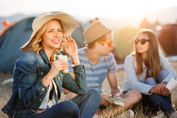 Teenagers sitting on the ground in front of tents, resting — Stock Photo, Image