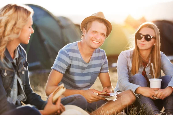 Teenagers sitting on the ground in front of tents, resting — Stock Photo, Image