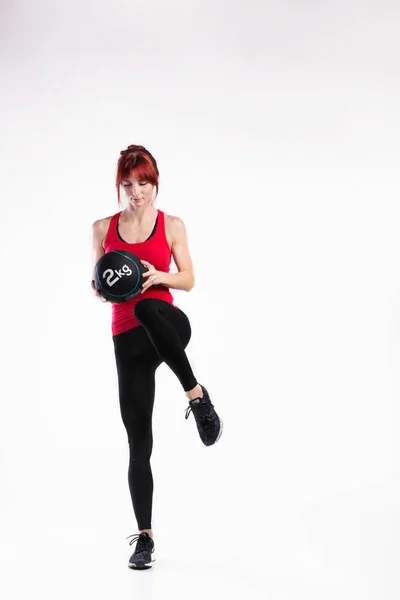 Mulher fitness em top tanque vermelho segurando bola medicina. Estúdio — Fotografia de Stock