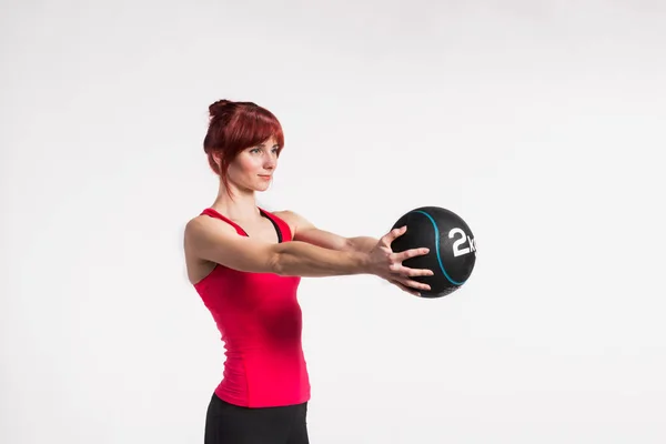 Fitness kvinna i röd tank top holding medicin boll. Studio skott — Stockfoto