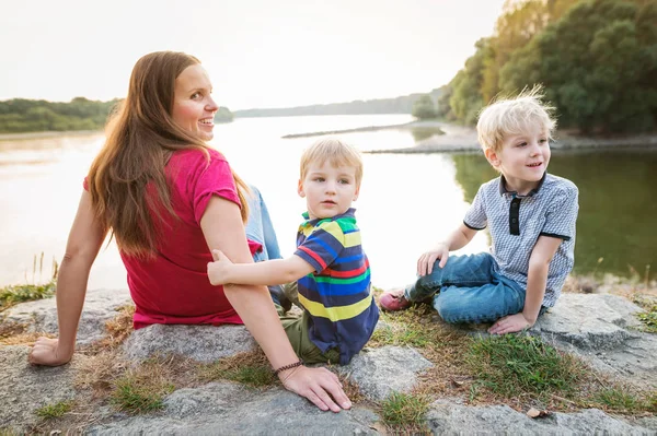 Μητέρα με δύο γιους στην λίμνη, ηλιόλουστη, ανοιξιάτικη ημέρα. — Φωτογραφία Αρχείου