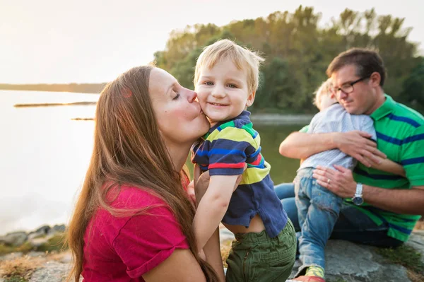 Familjen med två pojkar vid sjön, solig vårdag. — Stockfoto