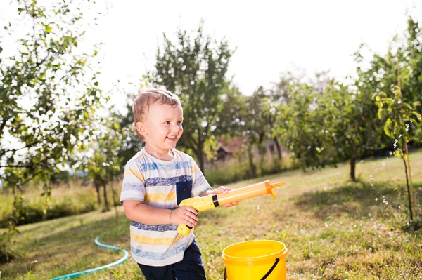 Niño con pistola de agua salpicando a alguien, soleado verano garde —  Fotos de Stock