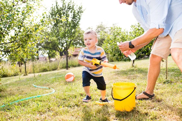 Petit garçon avec père jouant avec des pistolets à eau, éclaboussures — Photo