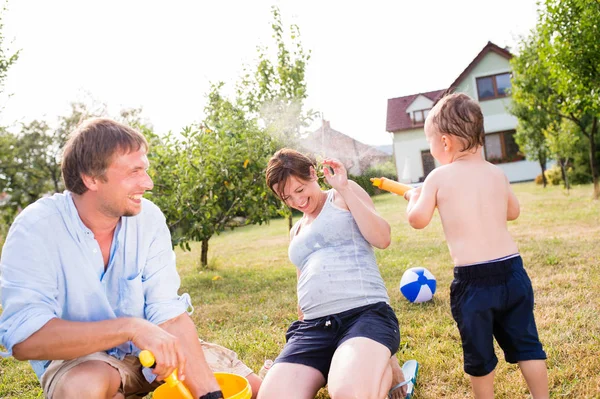 Pequeño niño con madre y padre salpicándose el uno al otro — Foto de Stock