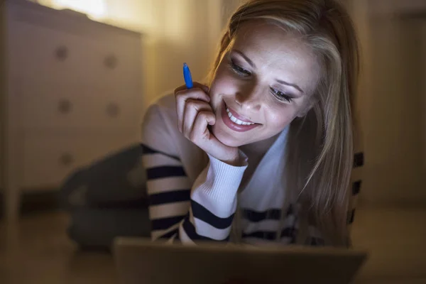 Vrouw liggend op de vloer, werken op de tablet bij nacht. — Stockfoto