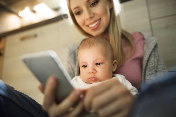 Beautiful mother with son in the arms, holding smartphone — Stock Photo, Image