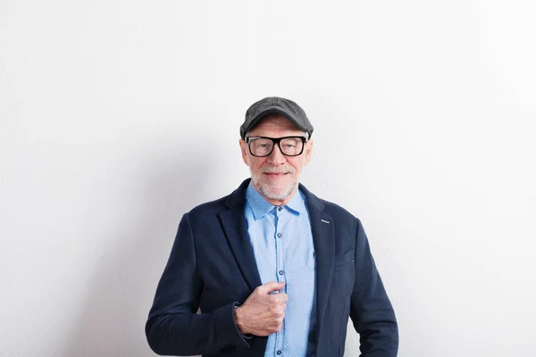 Uomo anziano in camicia blu, giacca, occhiali e cappello, ripresa in studio — Foto Stock