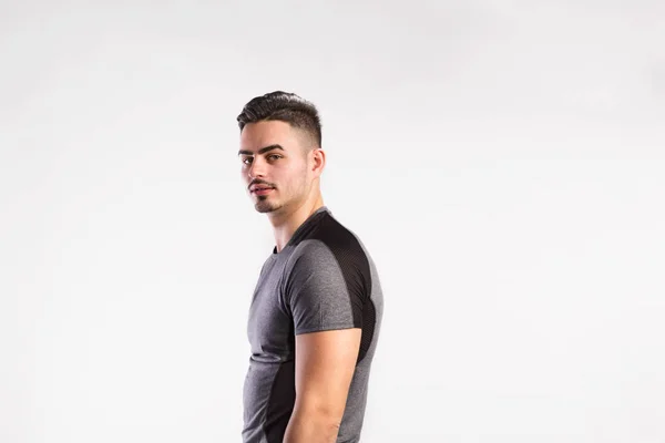 Jovem homem de fitness bonito em cinza t-shirt, tiro estúdio . — Fotografia de Stock