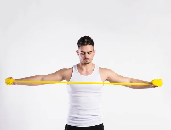 Bonito homem fitness trabalhando com elástico, tiro de estúdio . — Fotografia de Stock