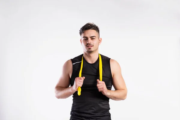 Schöner Fitness-Mann mit gelbem Gummiband, Studioaufnahme. — Stockfoto