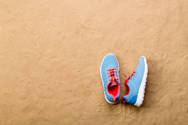 Sapatos esportivos azuis colocados na praia de areia, tiro estúdio — Fotografia de Stock