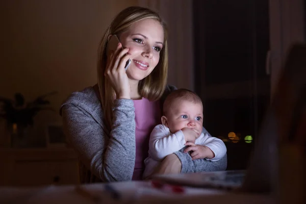 Madre con hijo en brazos, haciendo una llamada telefónica — Foto de Stock