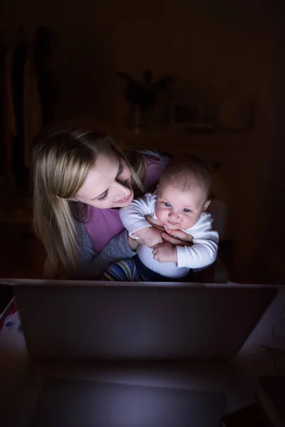 Matka z synem w ramionach, praca na laptopie — Zdjęcie stockowe