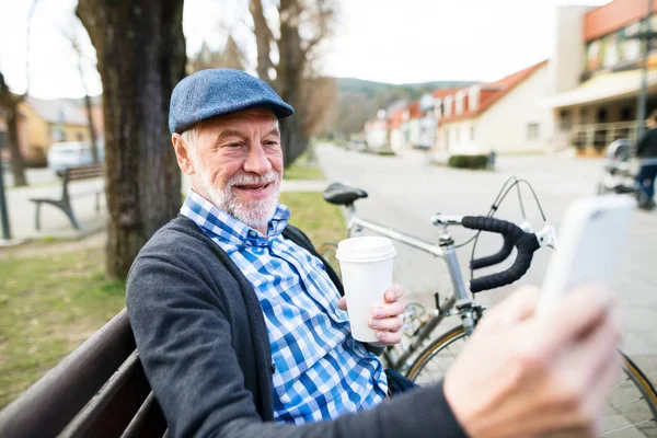 Hombre mayor con bicicleta en la ciudad, tomando selfie con teléfono inteligente —  Fotos de Stock