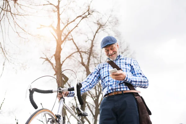 Hombre mayor con smartphone y bicicleta en la ciudad . —  Fotos de Stock