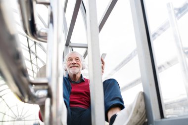 Üst düzey adam akıllı telefon ve pasajda oturan kulaklıklar.