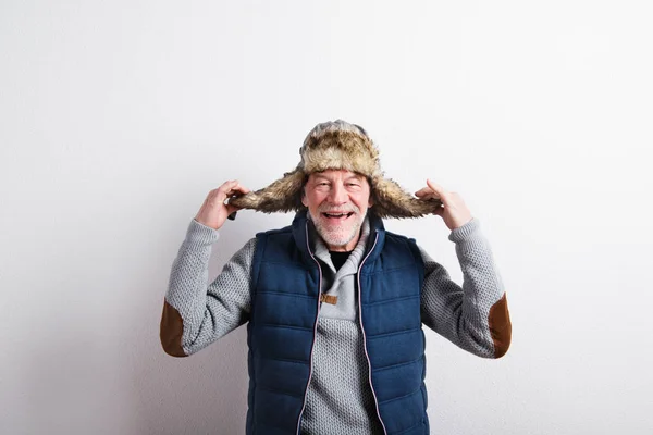 Uomo anziano in maglione, giubbotto e cappello di pelliccia, ripresa in studio . — Foto Stock