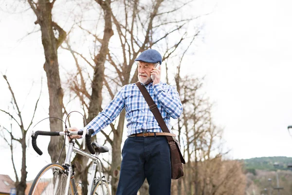 Старший мужчина со смартфоном и велосипедом в городе . — стоковое фото