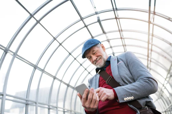 Äldre man med smartphone mot glas tak textning. — Stockfoto