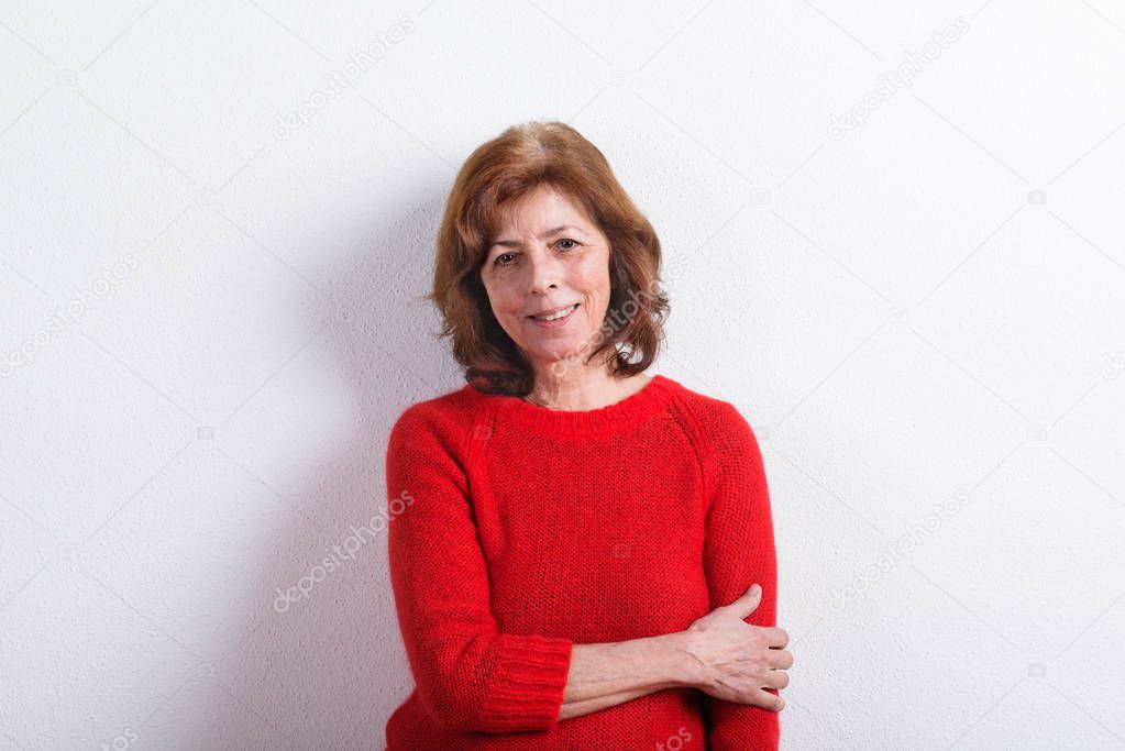 Beautiful senior woman in red sweater, studio shot.