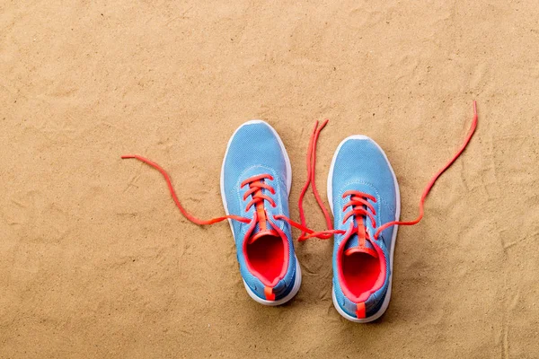 Sapatos esportivos azuis colocados na praia de areia, tiro estúdio — Fotografia de Stock