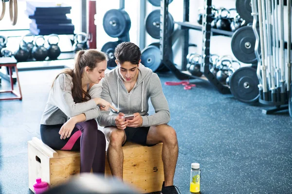 Ajuste pareja en moderno gimnasio crossfit con smartphone . — Foto de Stock
