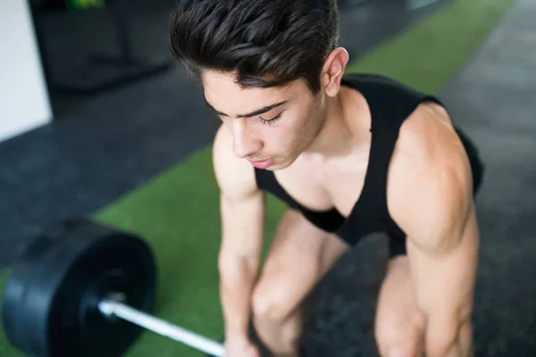 Jonge past Spaanse man in sportschool tillen van zware barbell — Stockfoto