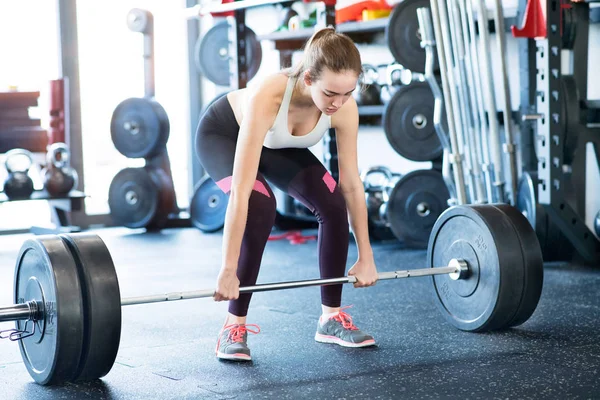 Bela jovem ajuste mulher no ginásio levantando pesado barbell — Fotografia de Stock