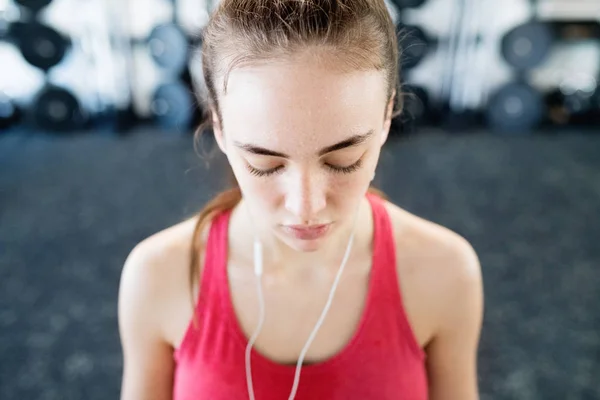 Giovane donna in palestra, auricolari nelle orecchie, ascoltare musica — Foto Stock