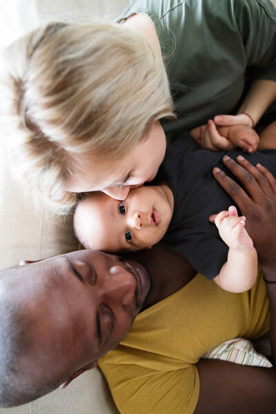 Young interracial family with little baby son at home.