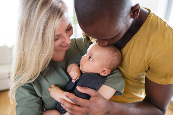 Young interracial family with little baby son at home.