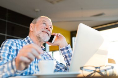 Smartphone ve kafede dizüstü ile üst düzey iş adamı