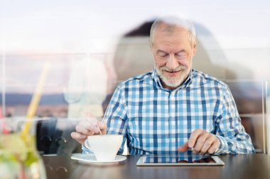 Kafede tablet üzerinde çalışan üst düzey iş adamı