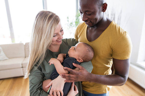 Young interracial family with little baby son at home.