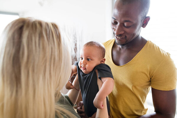 Young interracial family with little baby son at home.