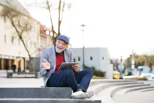 Pěkný starší muž s tabletem ve městě sedí na schodech. — Stock fotografie