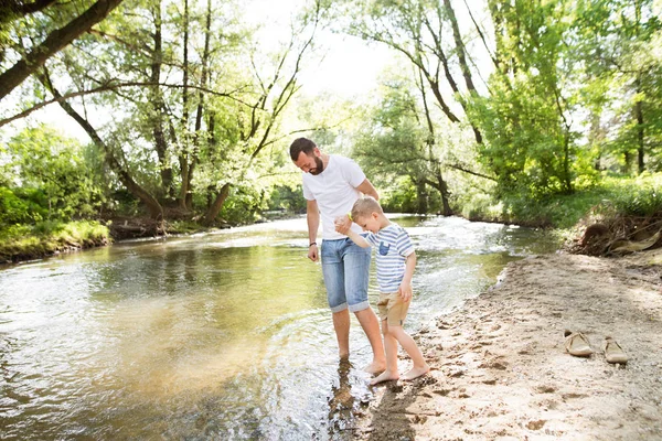 Unga far med liten pojke på floden, solig vårdag. — Stockfoto